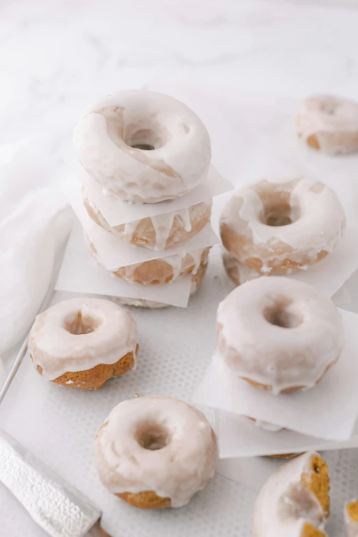 a variety of doughnuts sitting on paper and a knife