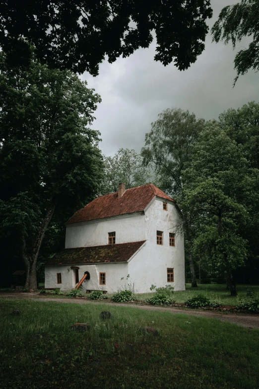 a white building with red tile roof sitting in the middle of trees