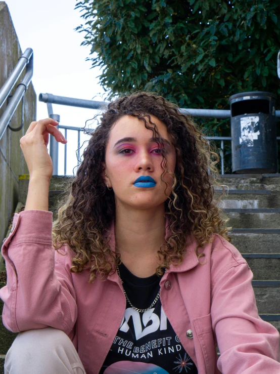 a girl with pink and blue makeup looks up from her steps