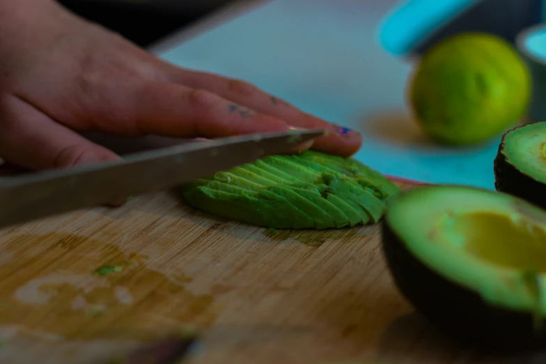 a hand chops up an avocado in half