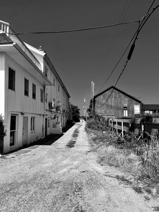 an old dirt road with telephone wires in front of a white building