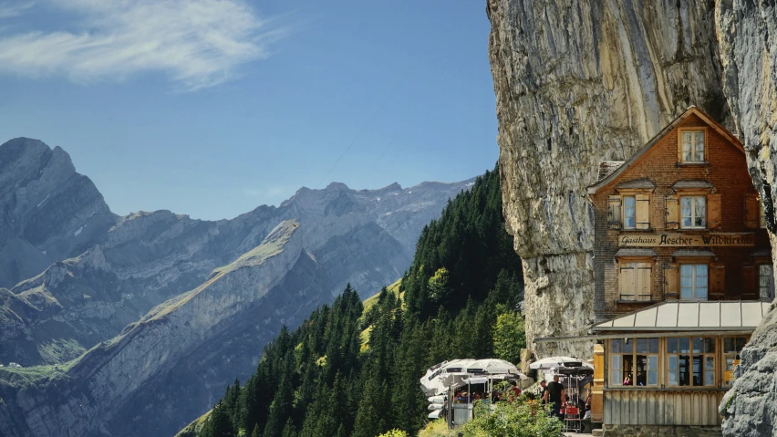 some people looking at a cabin next to some mountains