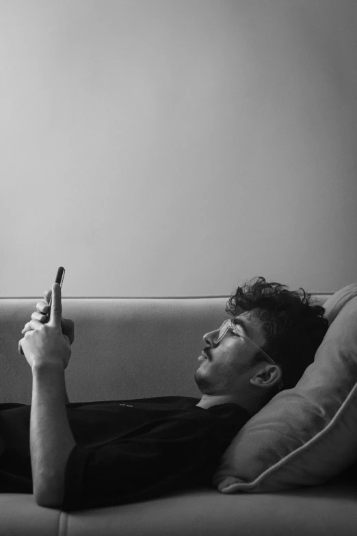 a man laying on a couch with a remote control in his hand