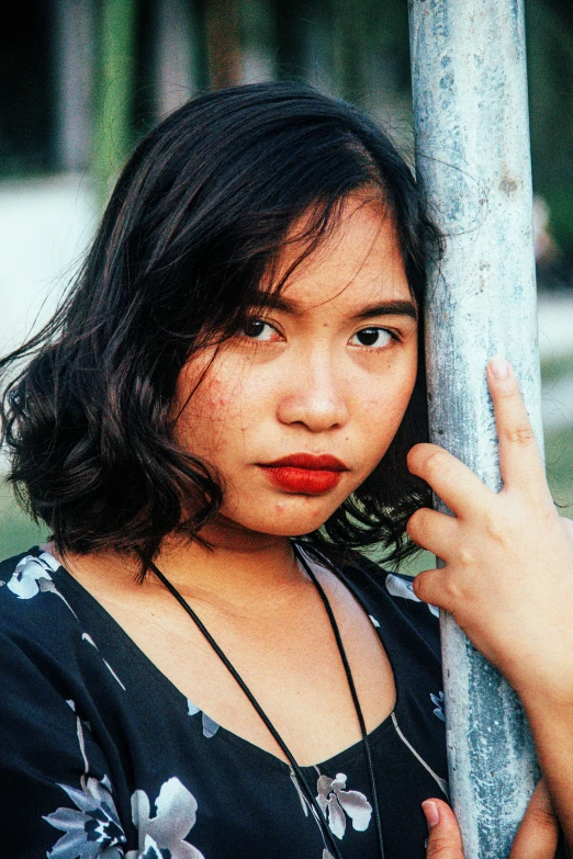 a young woman leaning against a tree with her arm on the trunk