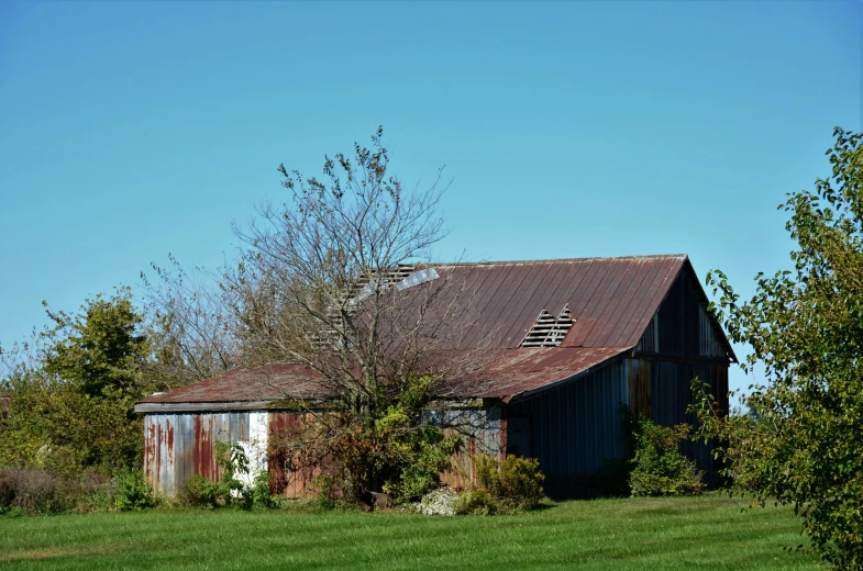 an old barn with a tin roof in a field