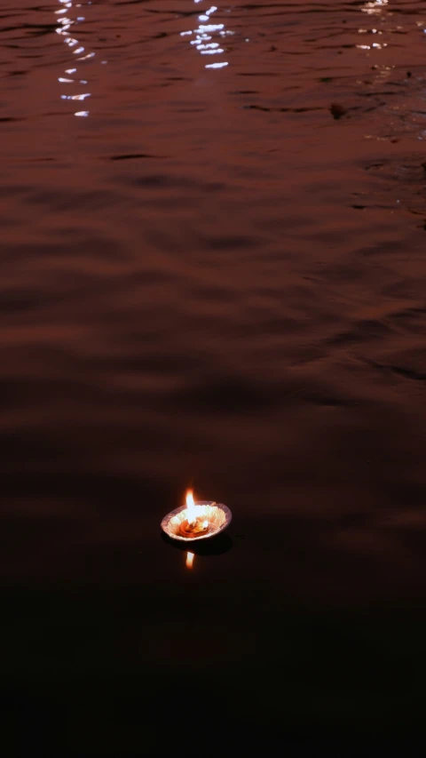 an illuminated candle floating on top of a lake