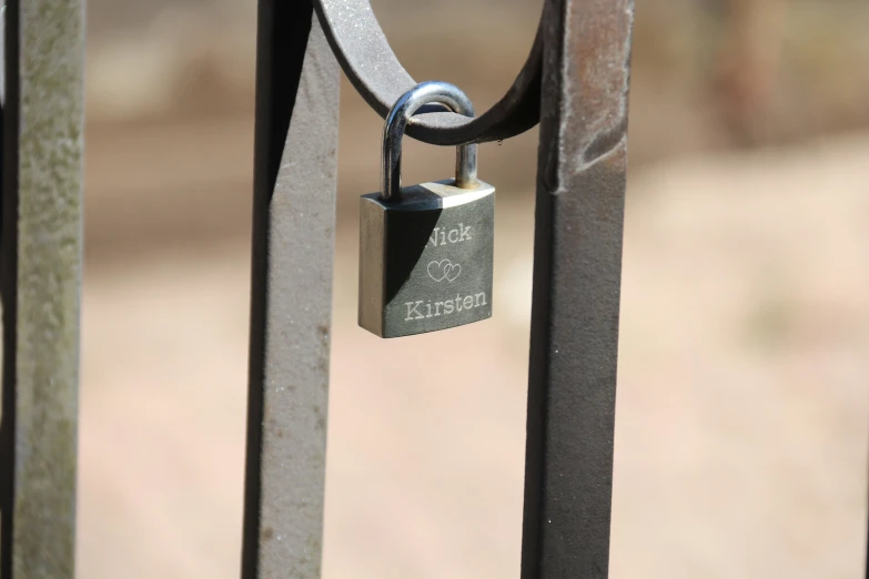 a small padlock hanging from a metal fence