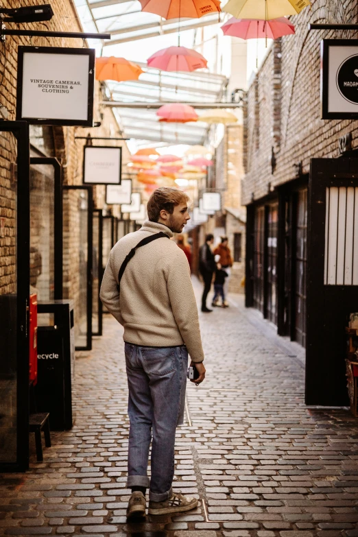 man walking down the middle of an alley way under an umbrella