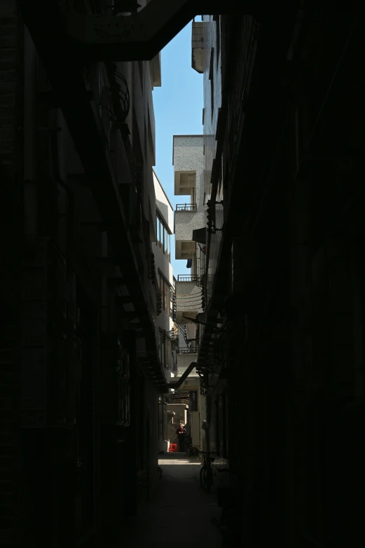 a narrow, dark alleyway with balconies and brick buildings