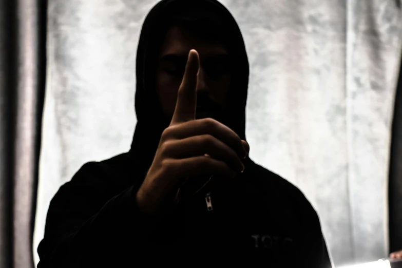 a person with a hooded jacket and a finger down pointing