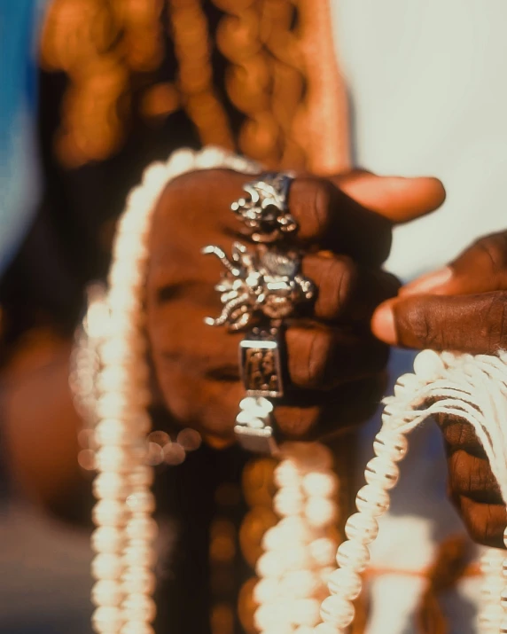 a person wearing celets holding a beaded wrist with a cross on it