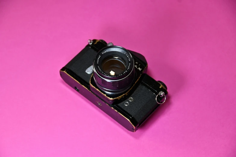 an old fashioned digital camera on pink background