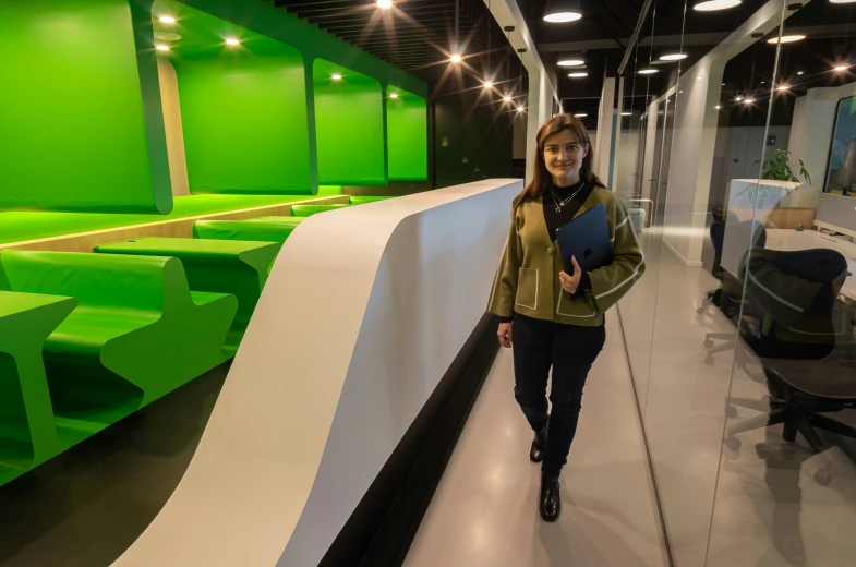 a woman walking through a room in front of green seats