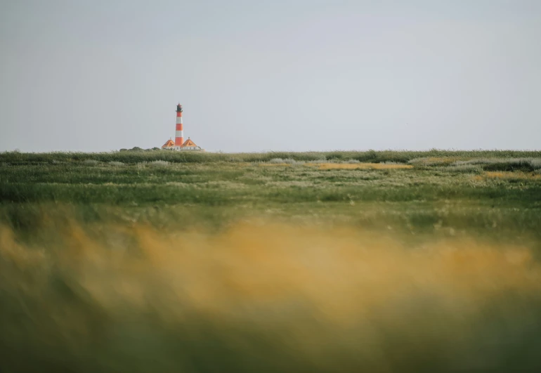 a large lighthouse on top of a hill in a field