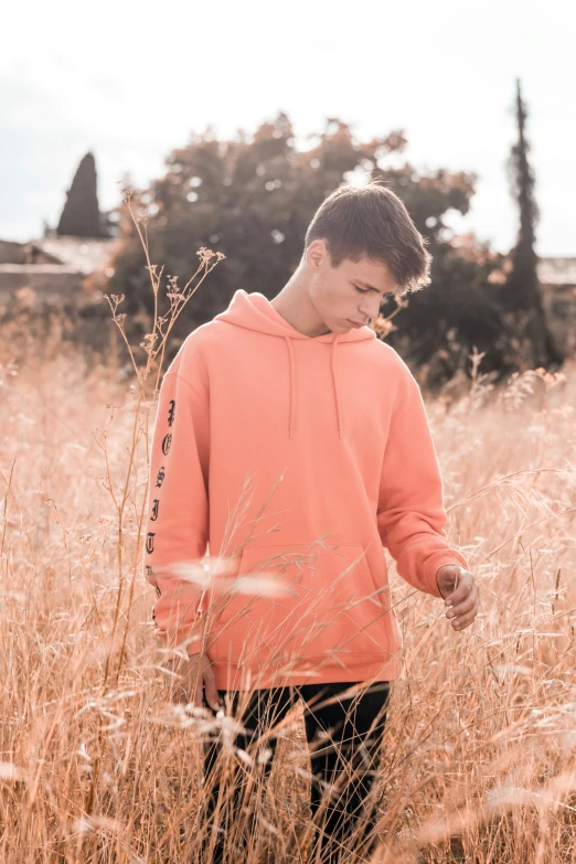 a boy is standing in some brown grass