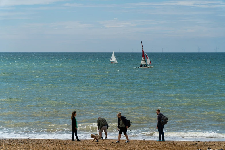 a group of people on the beach standing near the water