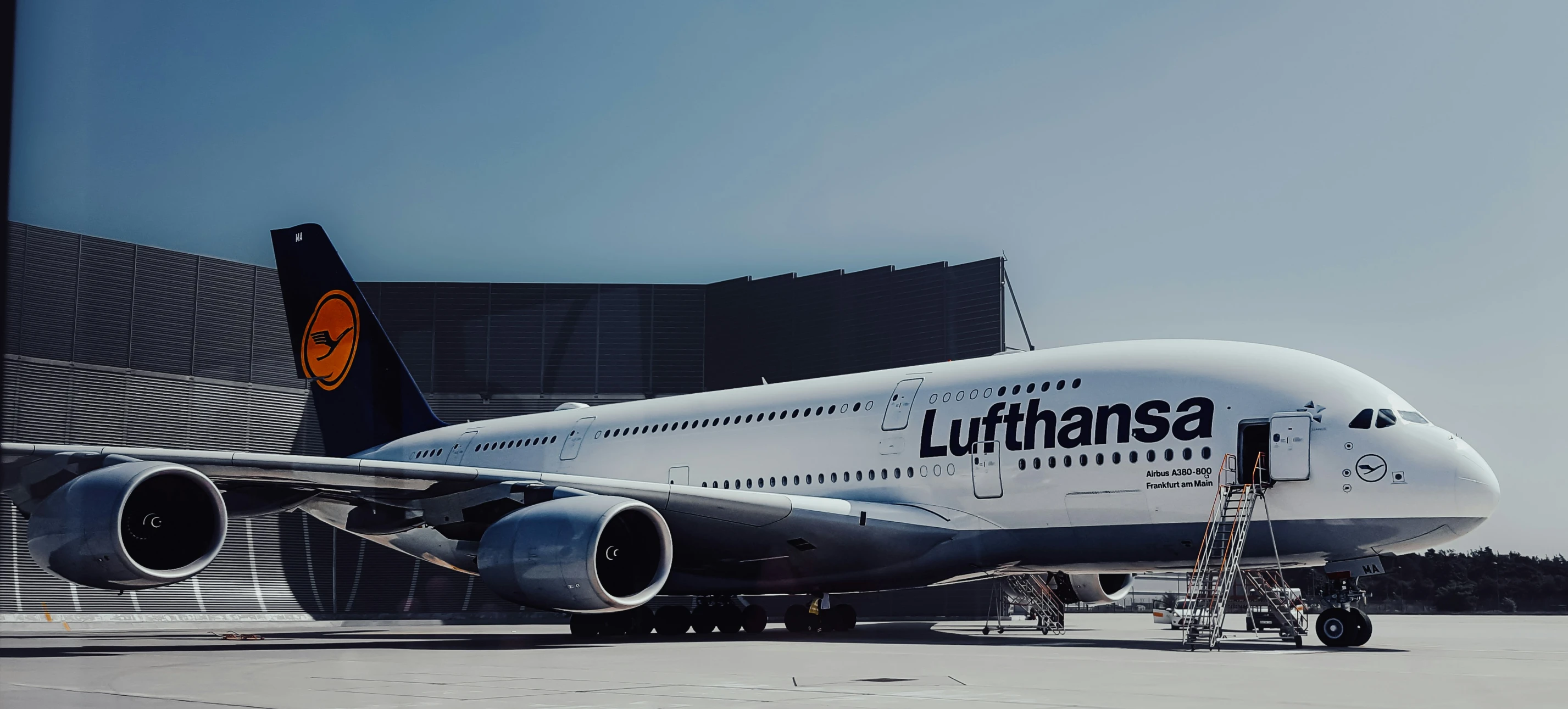 an airplane sitting on the runway with a building in the background