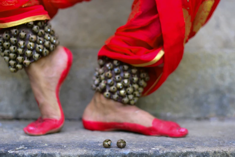 the legs of a woman in red shoes next to a gray concrete wall