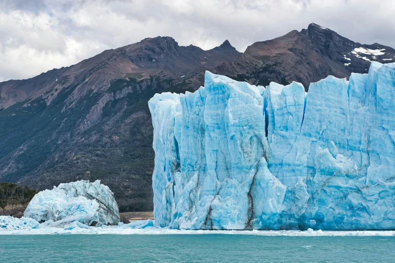 an iceberg on a shore line, with a mountain in the background