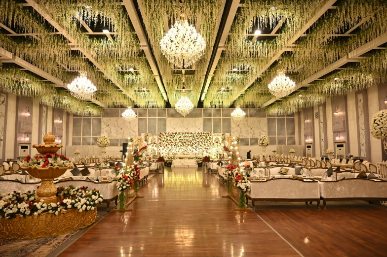 a banquet hall with white and gold linens, chandeliers, floral arrangements, and flowers