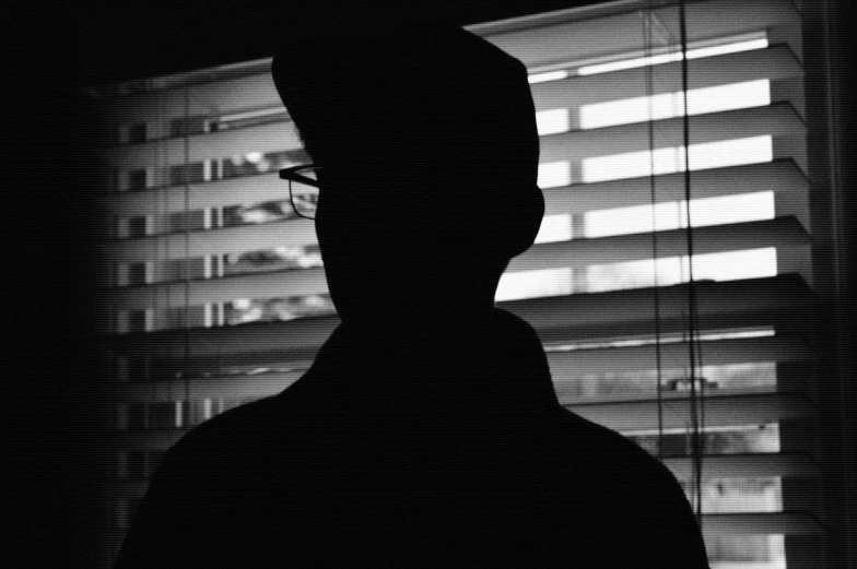 the shadow of a man in front of a window looking outside