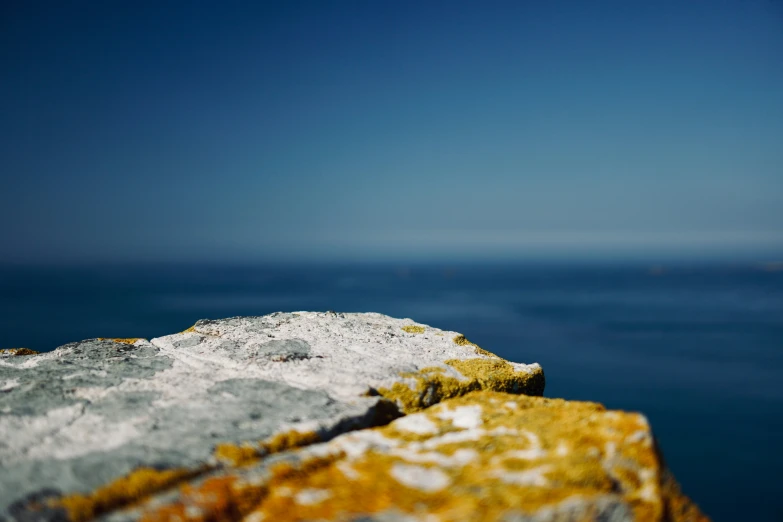 a bright orange rock is sitting on the edge of a cliff looking out over the water