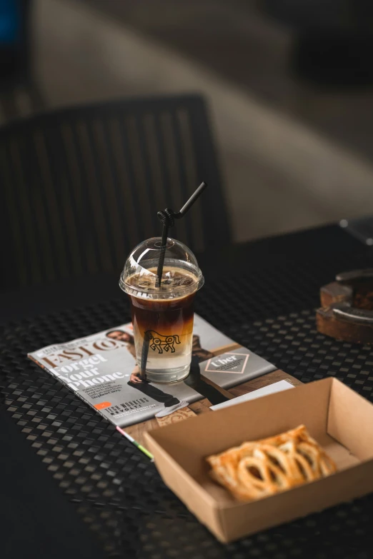 a table with a box of pizza and a drink