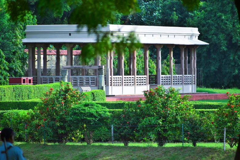 two women walking through a garden with a gazebo