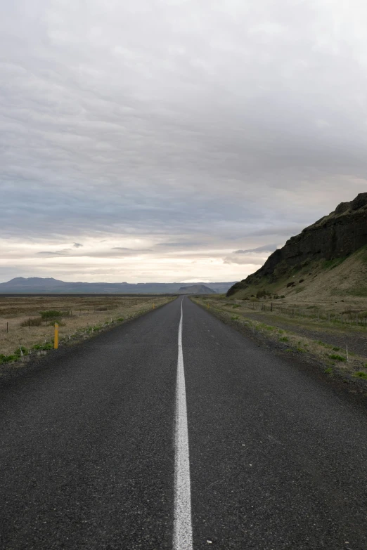 an empty road stretches into the distance with hills in the distance