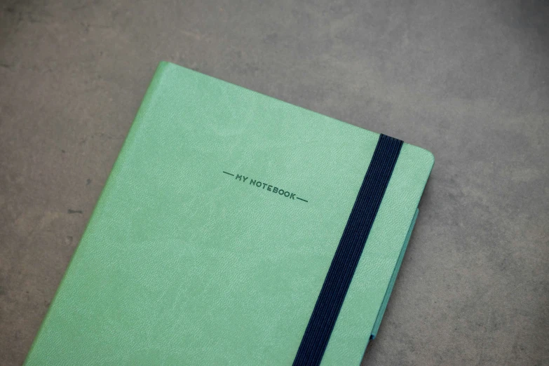 a green notebook with a black band on top