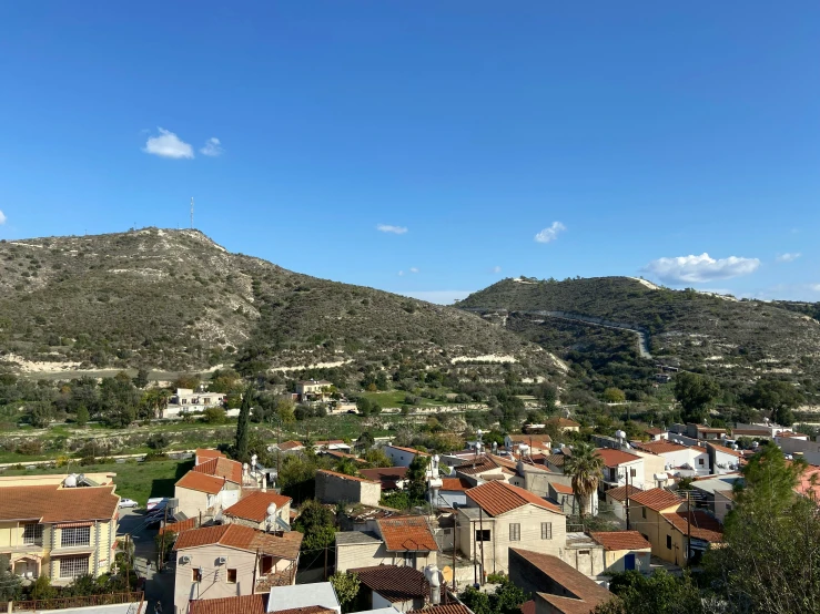 a hill view has buildings in the foreground and a small town below