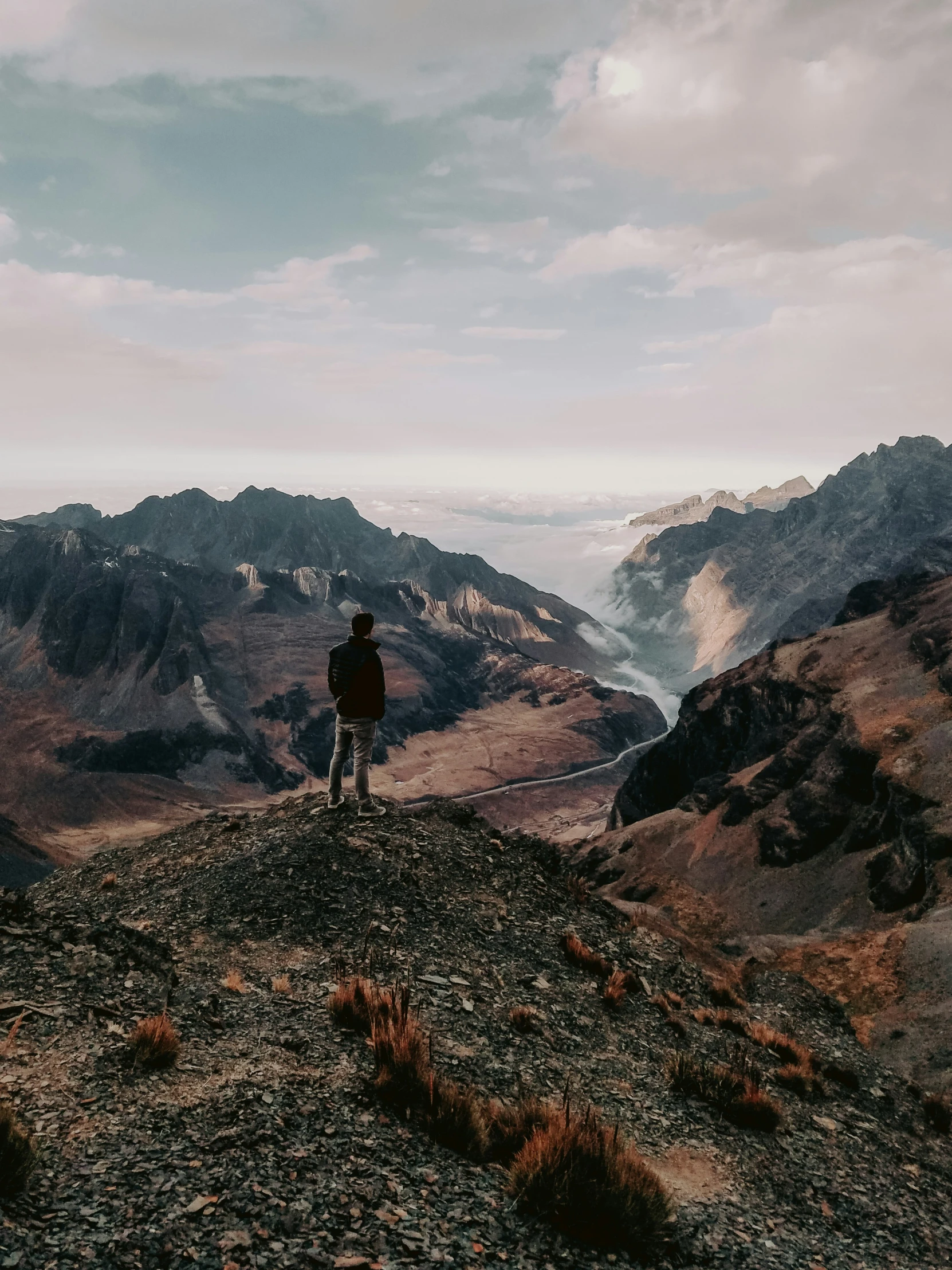 man standing on top of hill looking at the water