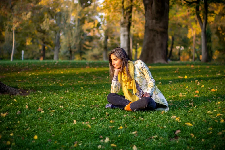a young woman in a park is sitting cross legged