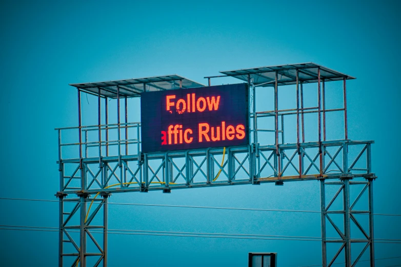 a large open area billboard with a red glow below it on a blue sky day