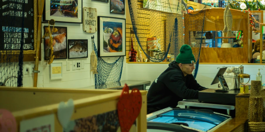 an older man wearing a green hat working on an old clock in a shop