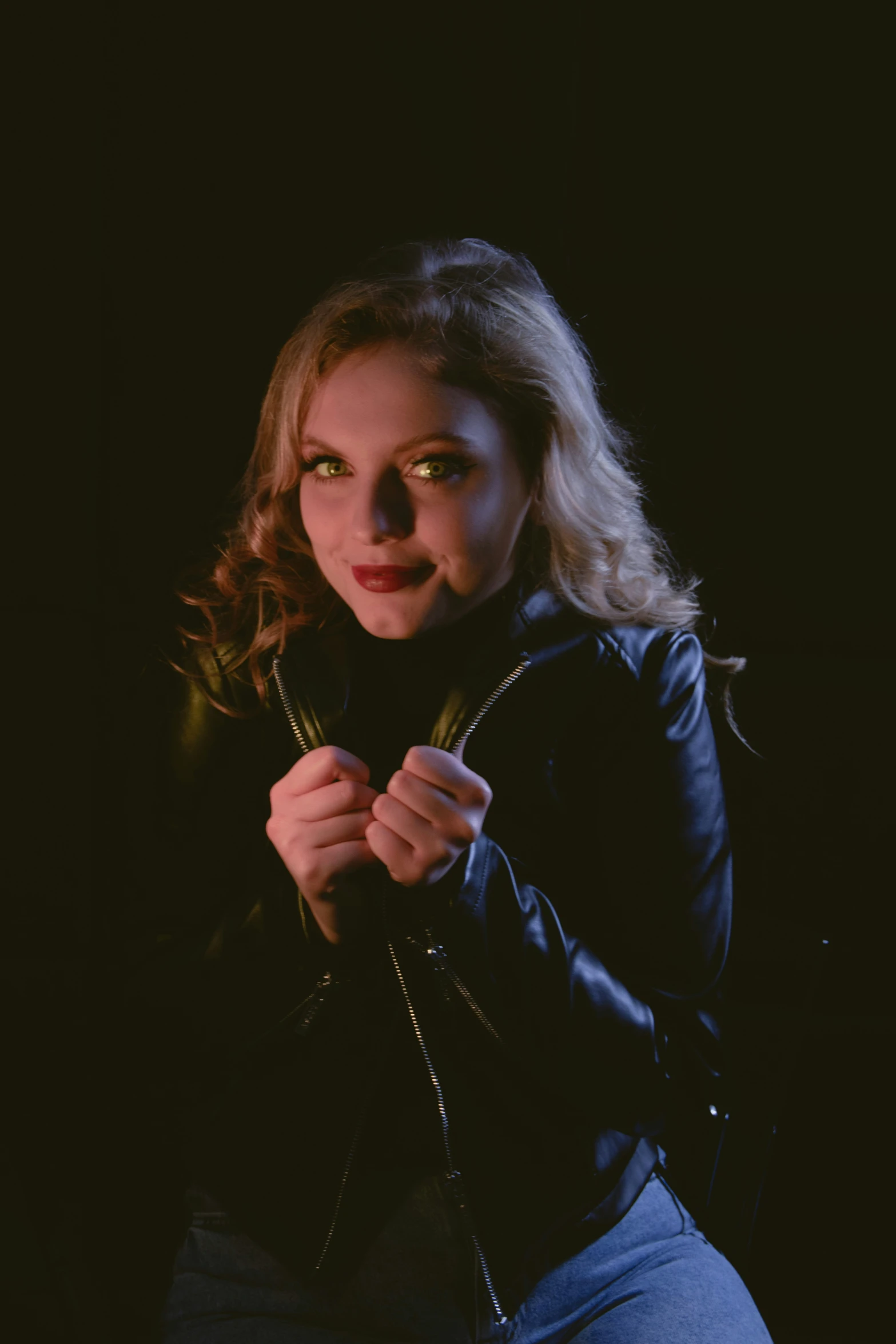 a woman in black leather jacket poses for a portrait