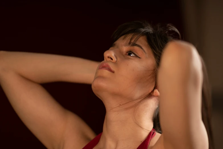 a young asian woman posing with her arm around her head