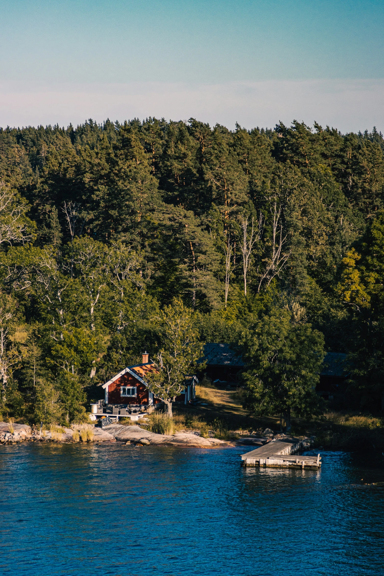 a red cabin sitting on the shore of a lake