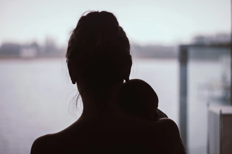 woman and child looking out at water in silhouette