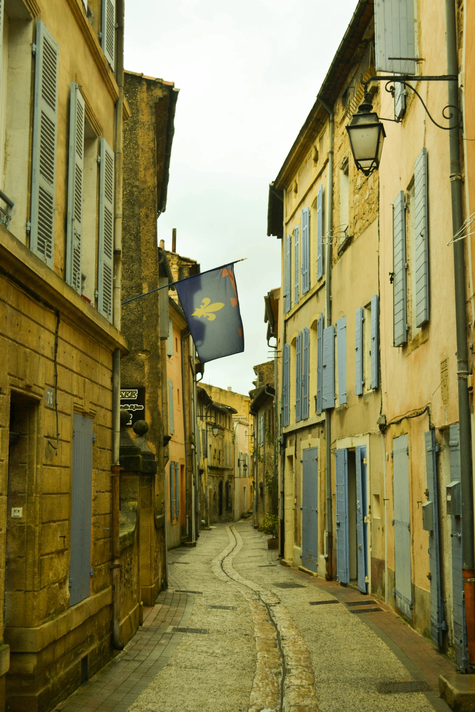 an empty narrow street with a flag and a street light