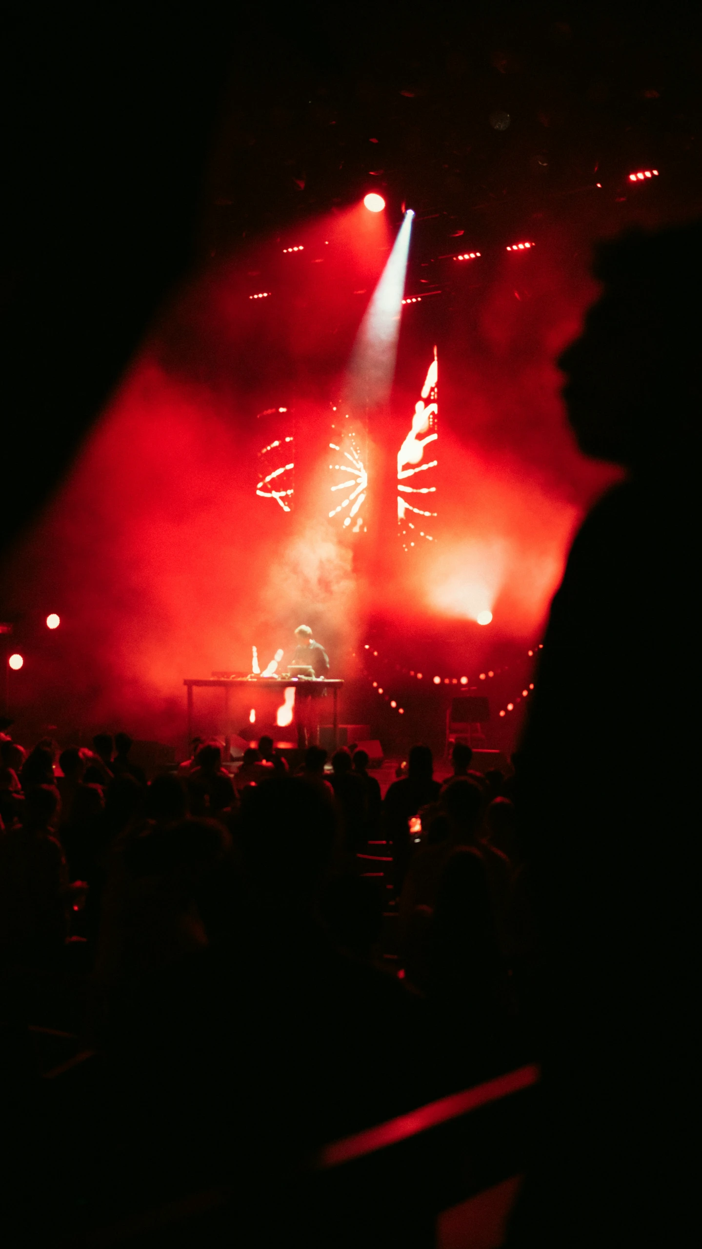 crowd watching fireworks on stage in dark, illuminated area