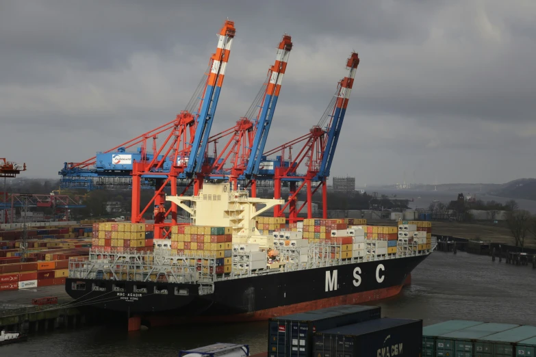 an ocean cargo ship has cranes attached to it