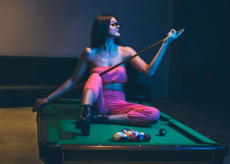 a woman in pink sitting on a pool table