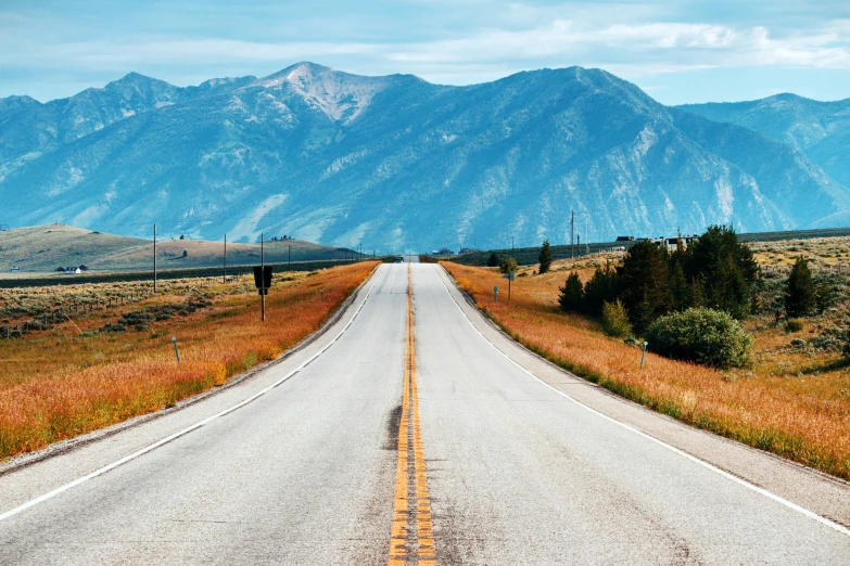 a road in the mountains with the grass and dirt on either side