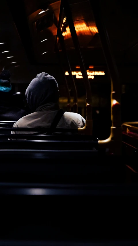 a bus seat that is full of people and it appears dark