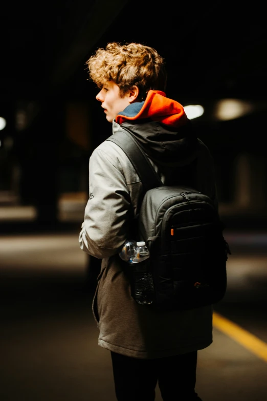 a boy waits to cross the street at night