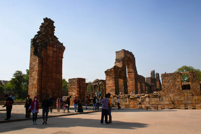 people walking by some ruins in a park