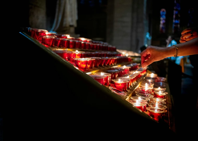 a candle vendor has arranged up rows of red votive candles