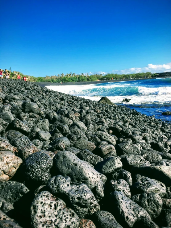 large boulders that are on the beach next to the water