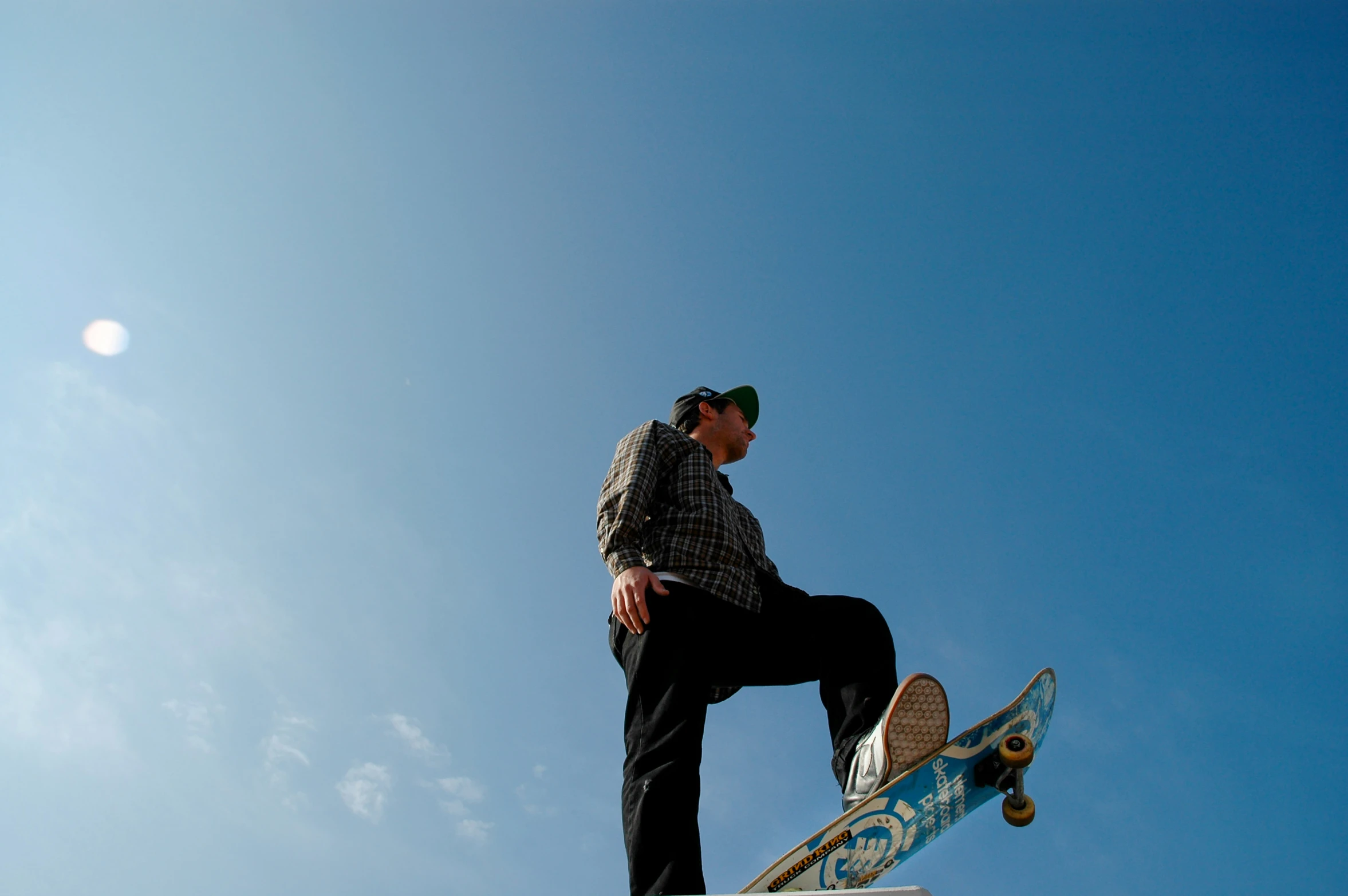 a man in plaid shirt doing a trick on a skateboard